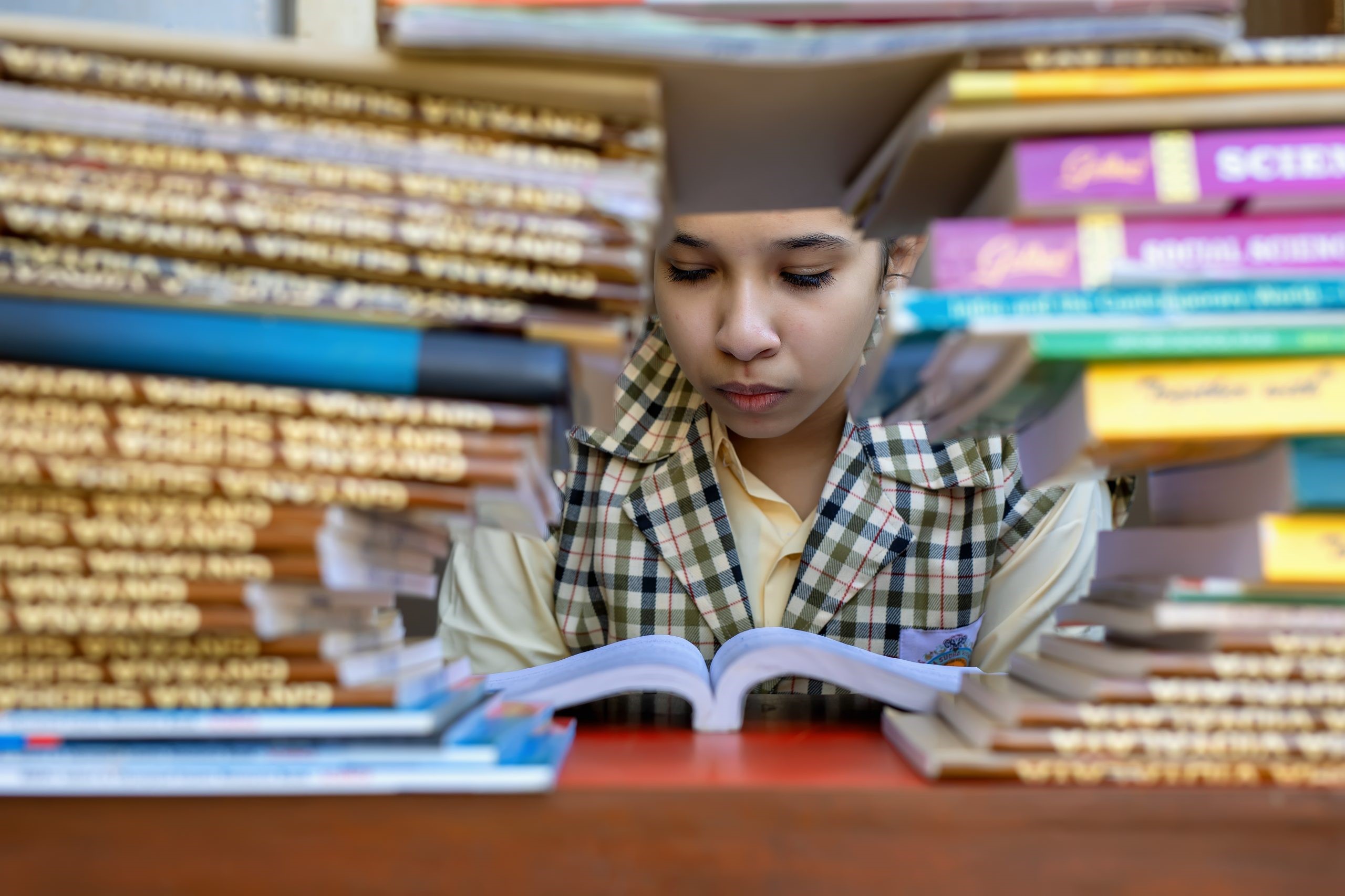 Menina lendo, atrás dos livros. Imagem ilustrativa texto nota no Ideb.