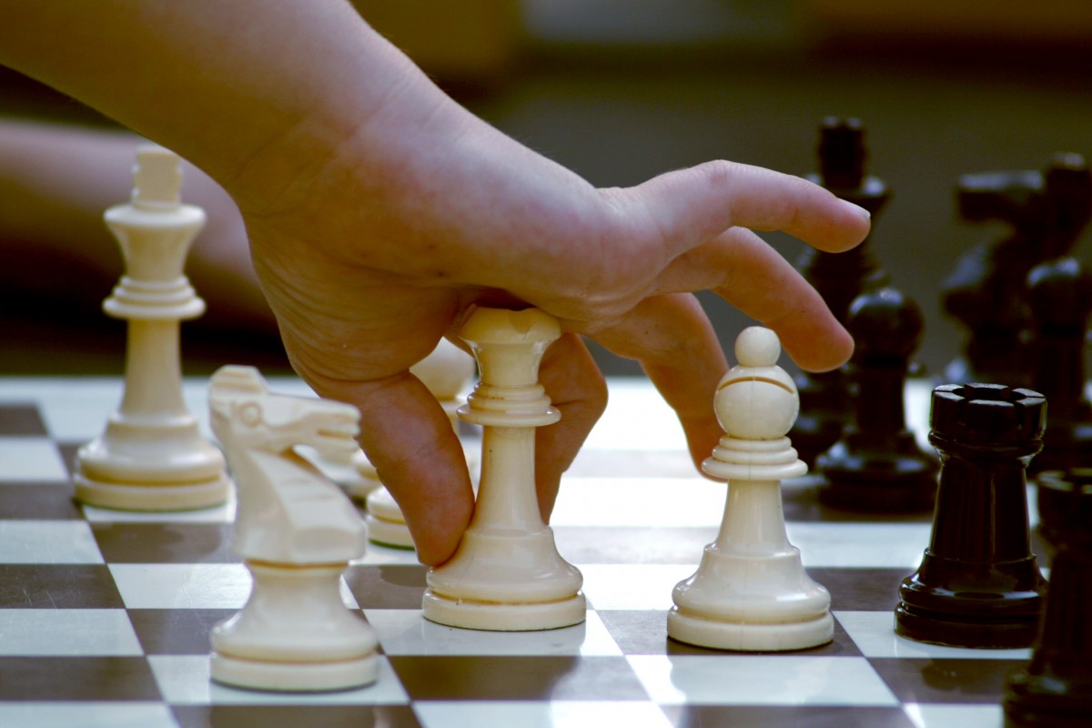 Mão de criança jogando xadrez. Imagem ilustrativa texto ensinar xadrez para crianças.