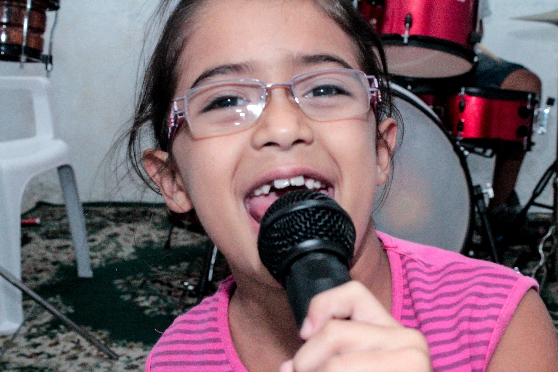 Menina cantando no microfone. Imagem ilustrativa texto brincar de karaokê.