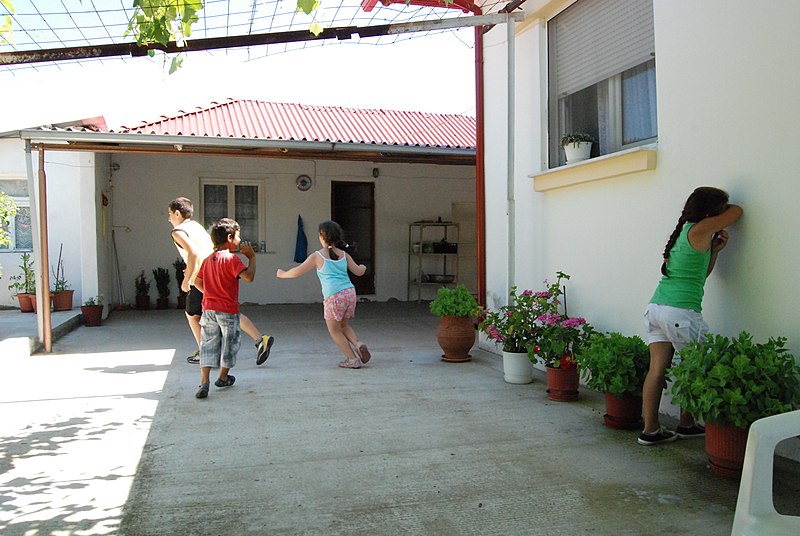 Crianças brincando de pega-pega no quintal. Imagem ilustrativa texto brincadeiras com nomes diferentes.