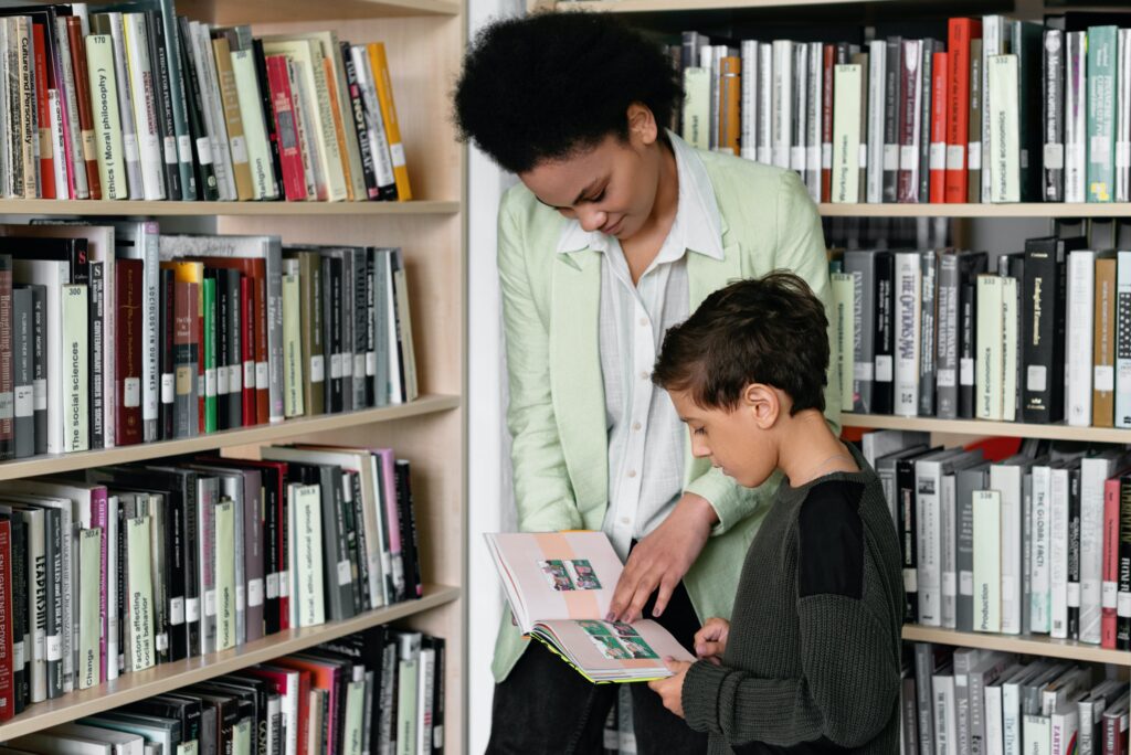Mulher com menino na biblioteca. Imagem ilustrativa texto bibliotecário.