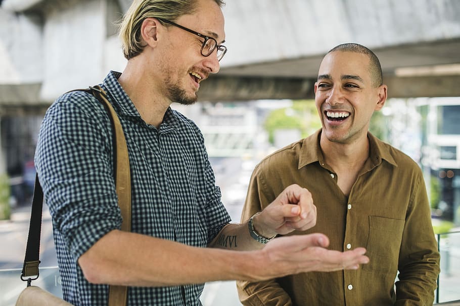Dois homens conversando e rindo. Imagem ilustrativa texto ler enriquece vocabulário.